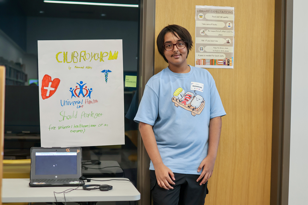 a boy poses for a photo next to his poster