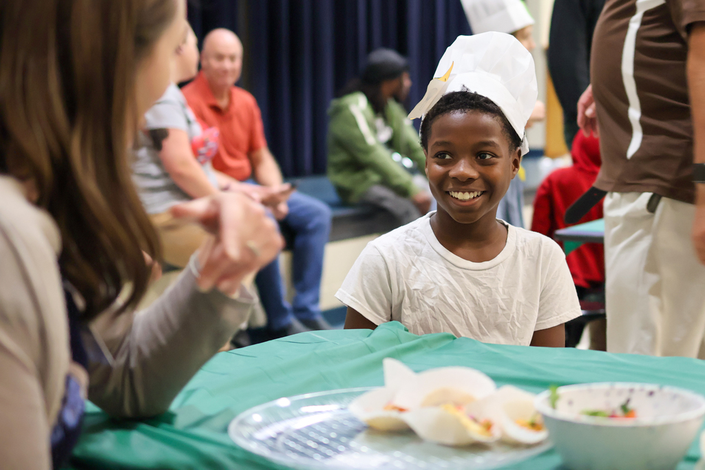 a boy in a chef hat smiles at a woman