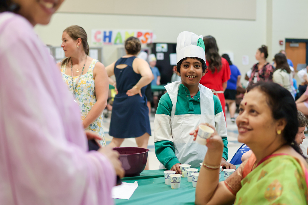 a boy in a chefs hat smiles at the camera