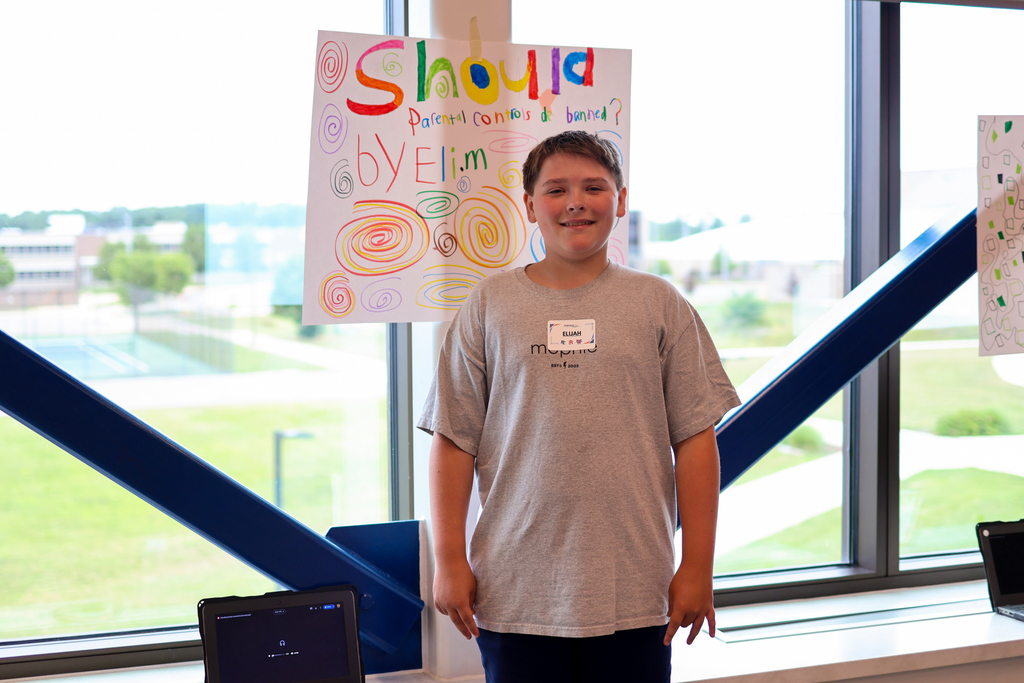 a boy poses for a photo in front of his poster