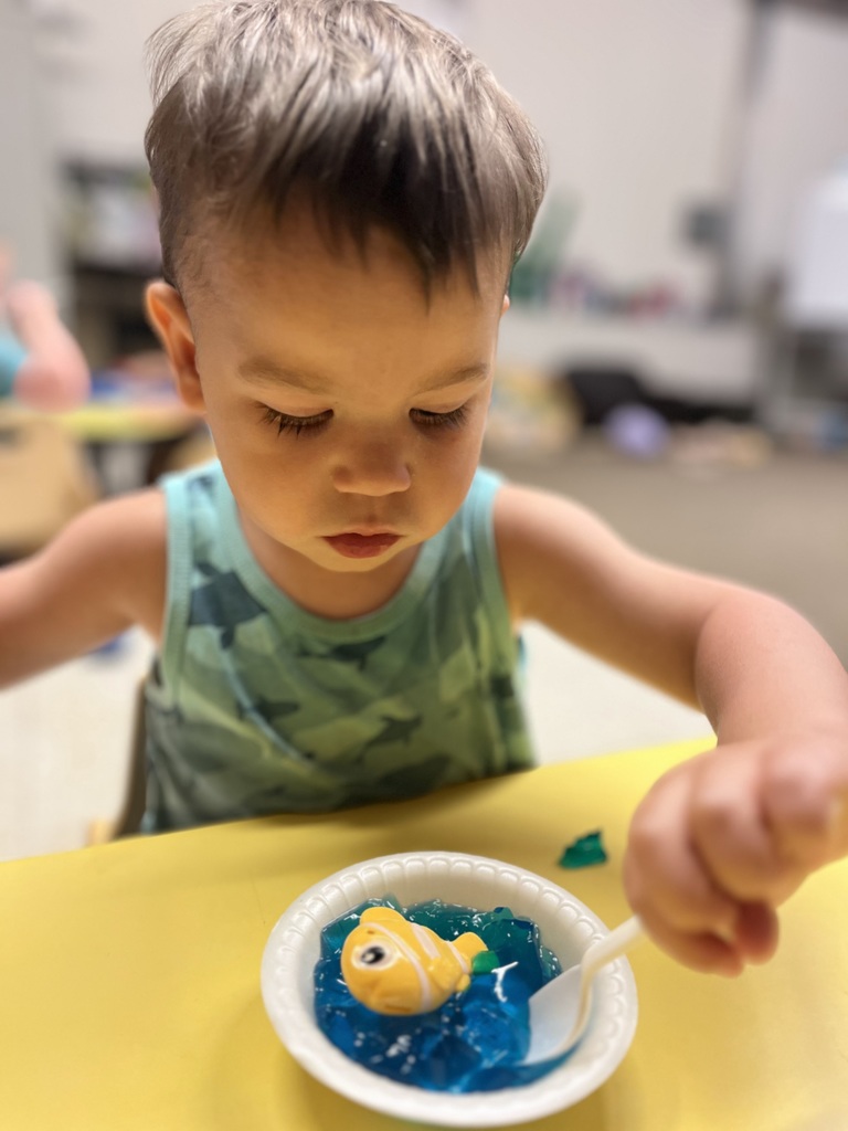 A 2 year old eating blue colored jello.