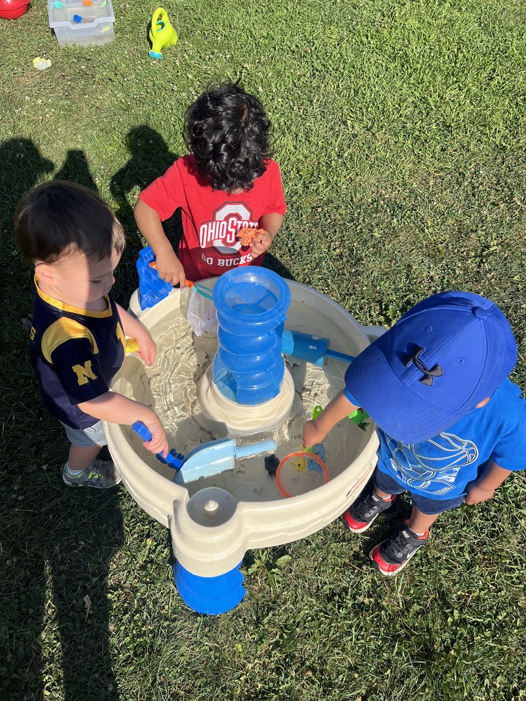 Three toddlers playing at the ocean table together.