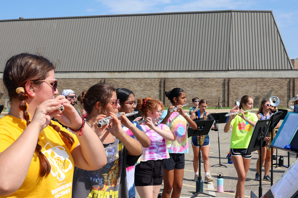 students playing musical instruments outside in a parking lot