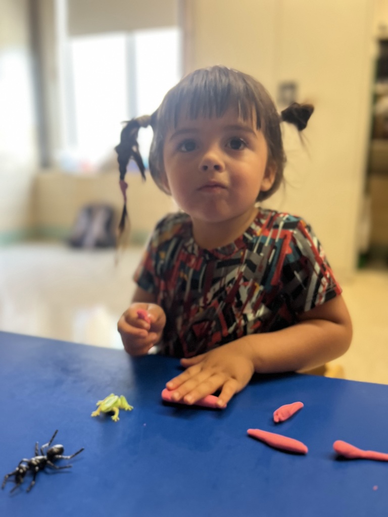 A female girl playing with playdough at a table.