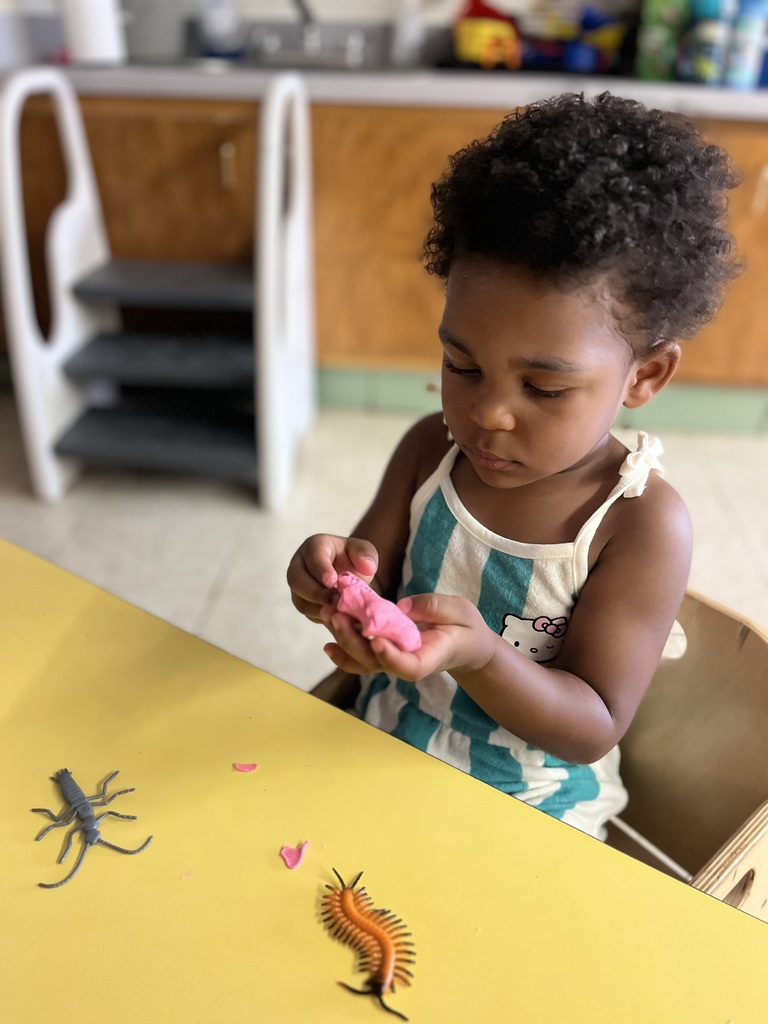 A female toddler playing with toy bugs.