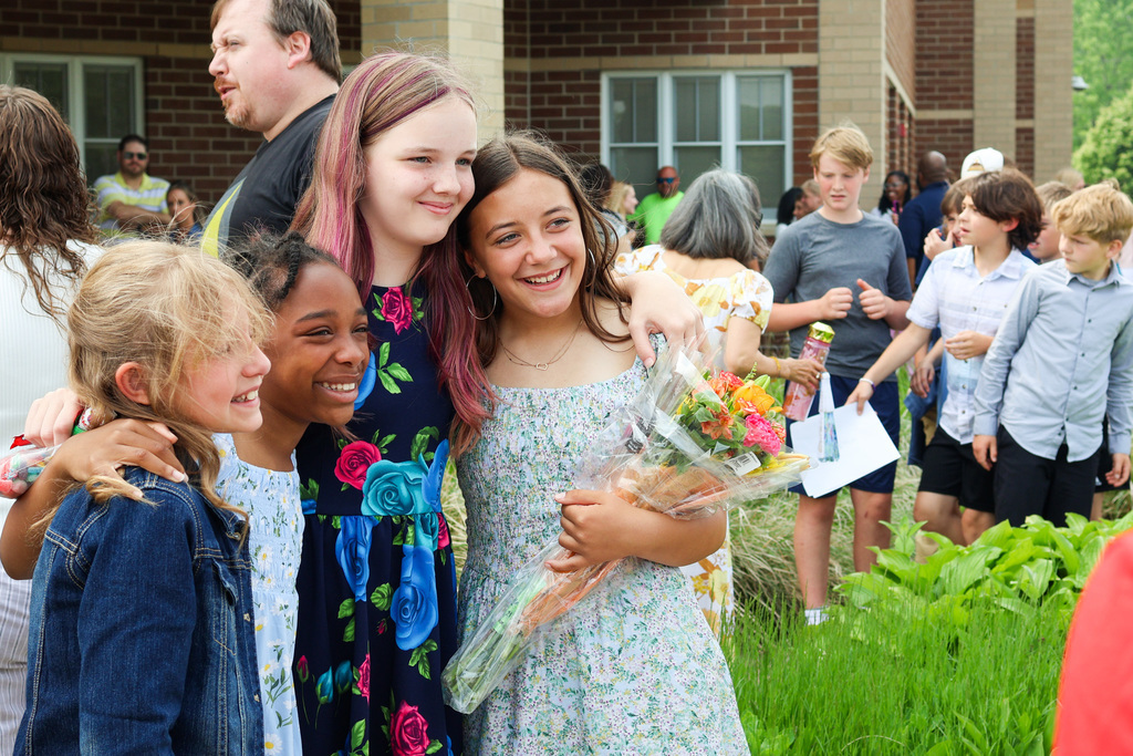 four girls pose for a photo outside an elementary school