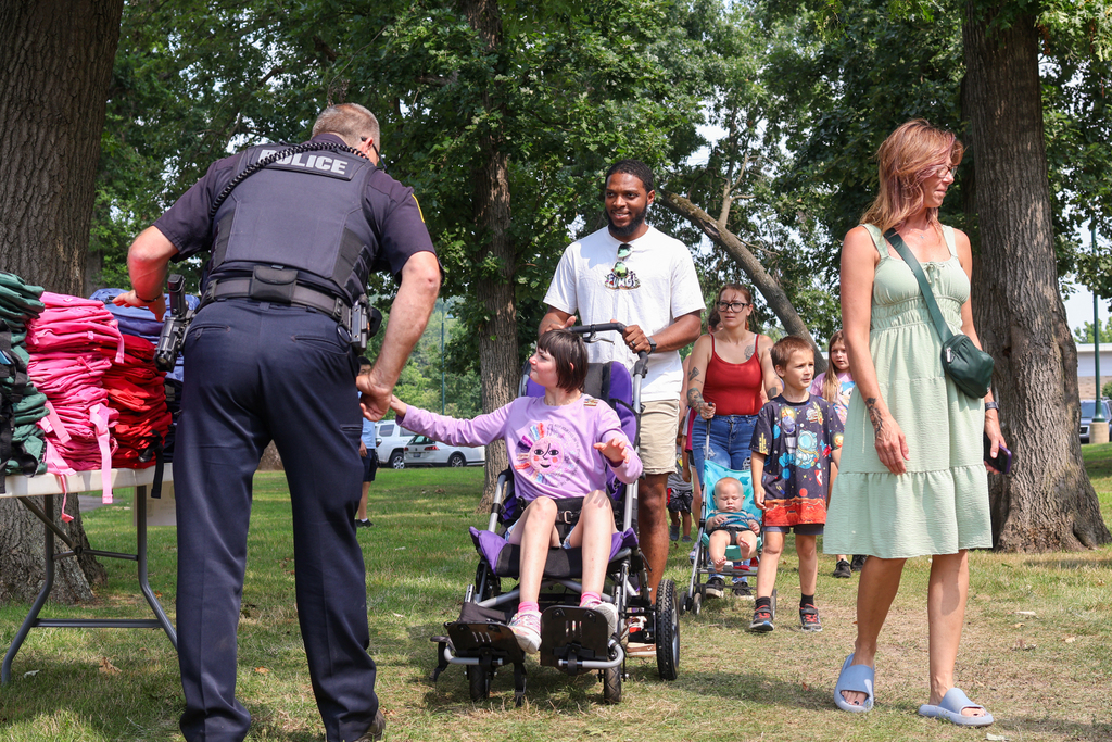 a girl in a wheelchair gets a backpack from a police officer