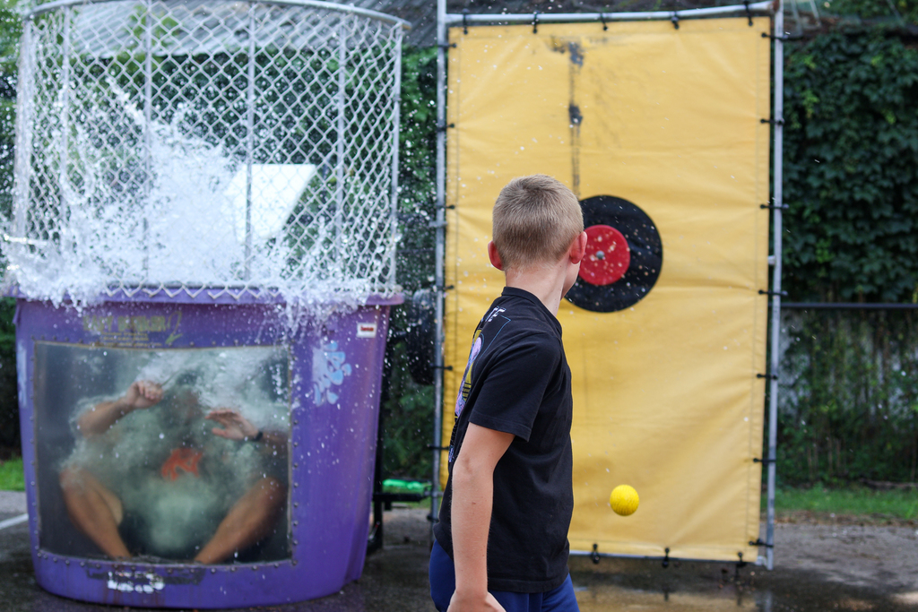 a boy watching a person fall in a dunk tank after hitting the target