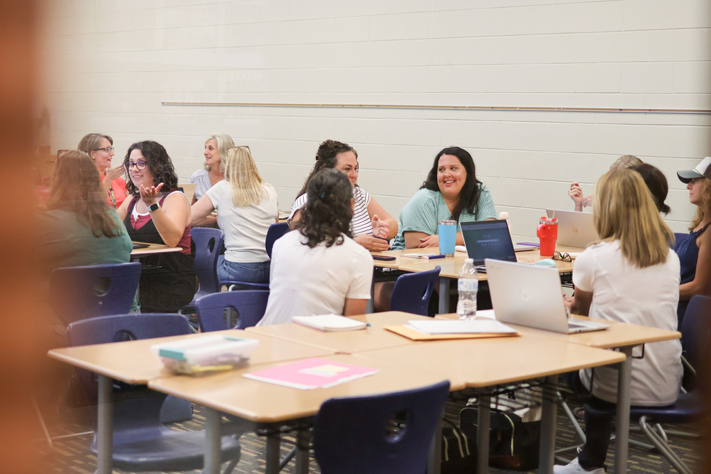 people sitting around desks talking in a classroom
