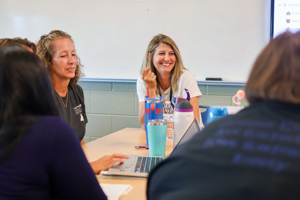 women sitting around a classroom desk in discussion