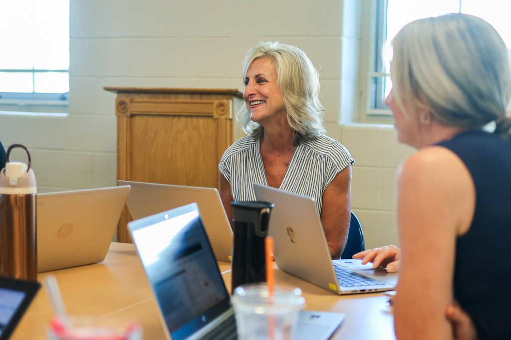 women sitting around a classroom desk in discussion
