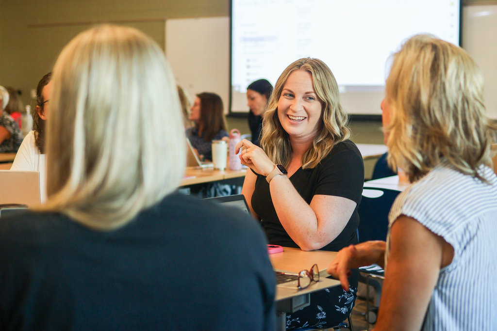 women sitting around a classroom desk in discussion