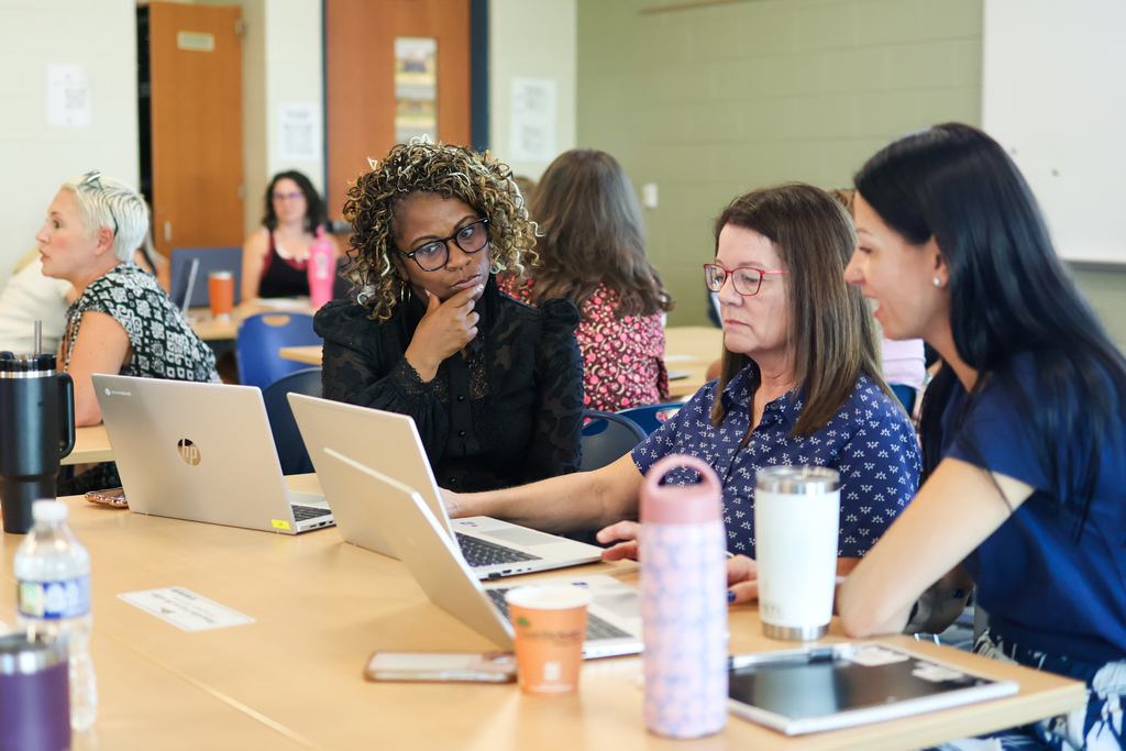 women sitting around a classroom desk in discussion