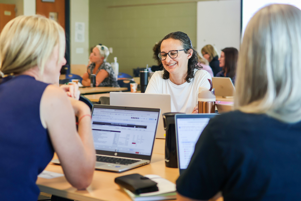 women sitting around a classroom desk in discussion