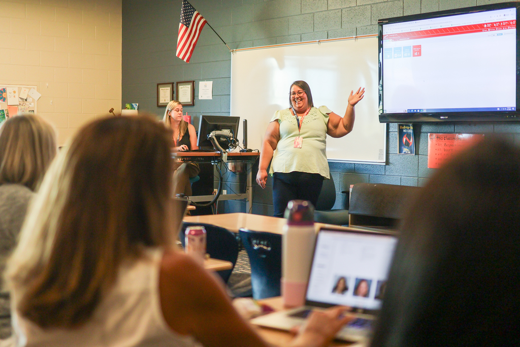 a woman teaching at the front of a classroom