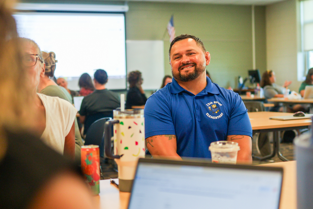 a man sitting around a classroom desk in discussion