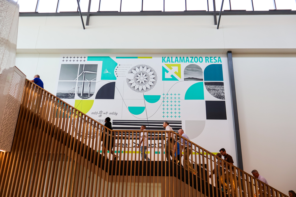 people walking up a flight of stairs in front of a large sign that says kalamazoo resa 