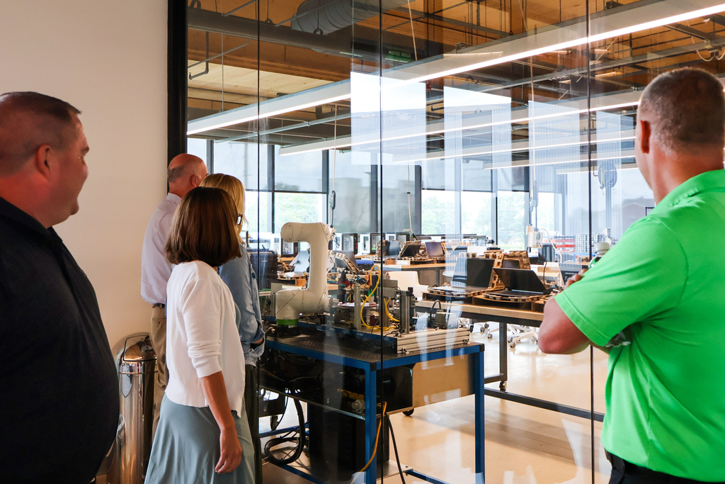 a group of people look through a glass window into a classroom
