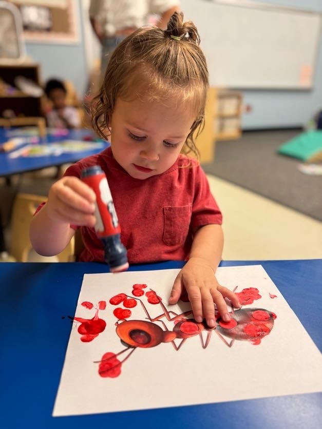 Kid painting a ant with red paint.
