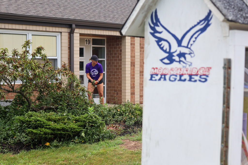 a woman gardens outside a school