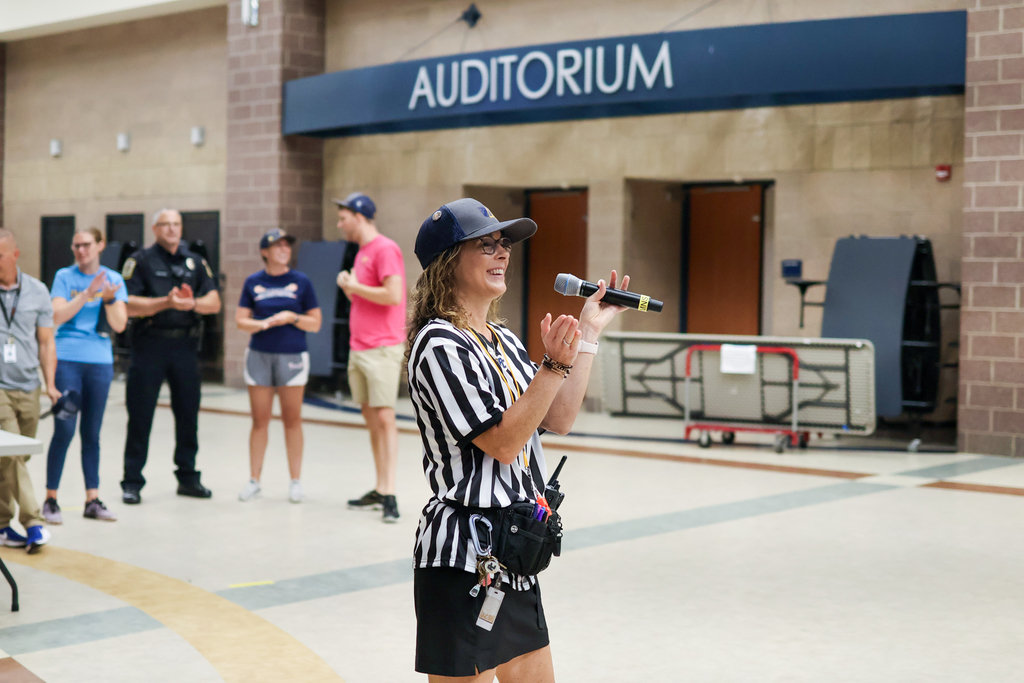 a woman in a ref outfit standing in a school cafeteria