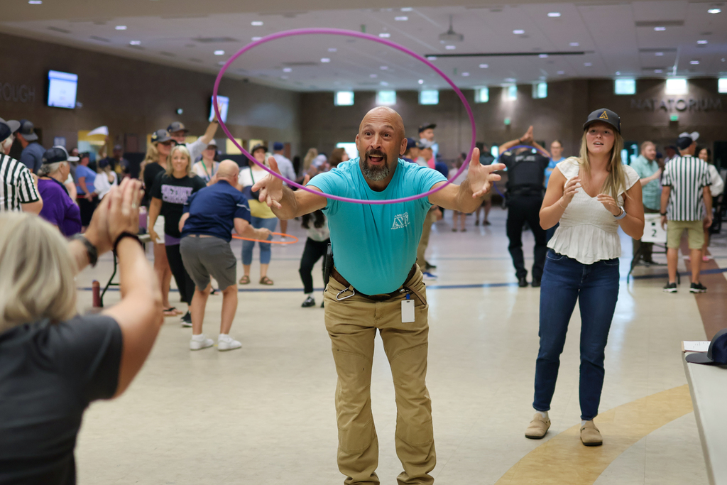 a man throws a hula hoop toward a human target in a school cafeteria
