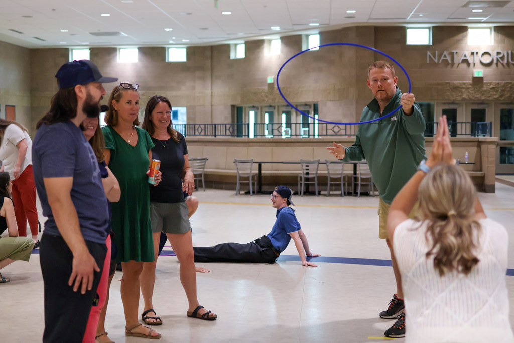 a man throws a hula hoop toward a human target in a school cafeteria