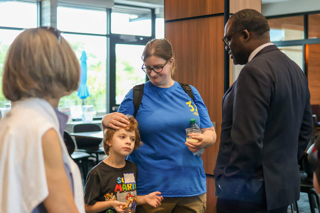 a woman and her child stand and talk to a man