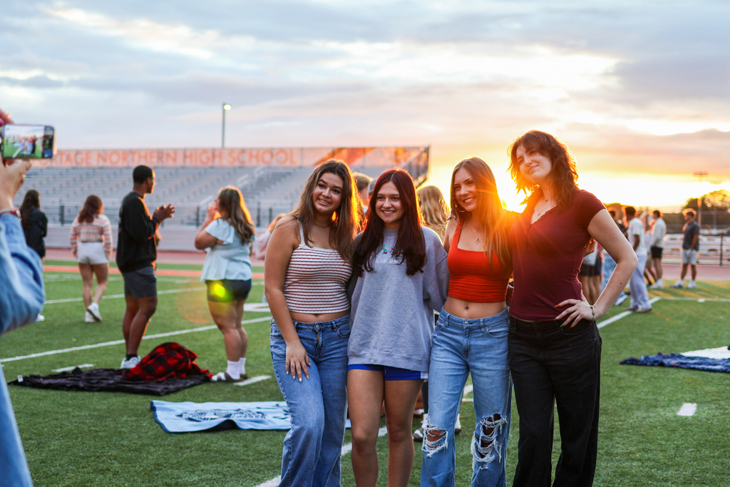 four girls pose for a photo in front of a sunrise