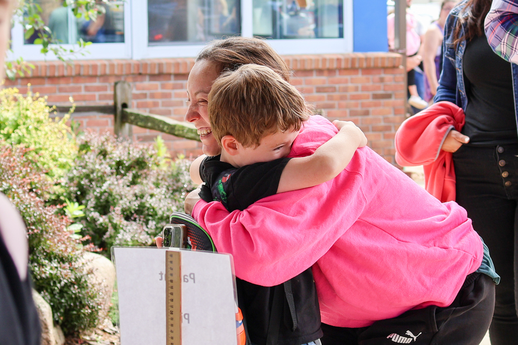 a mom hugs her son outside a school