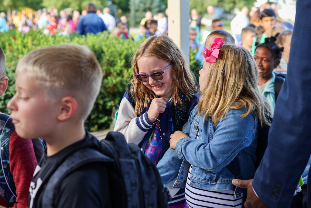 two girls smiling as they walk into a school