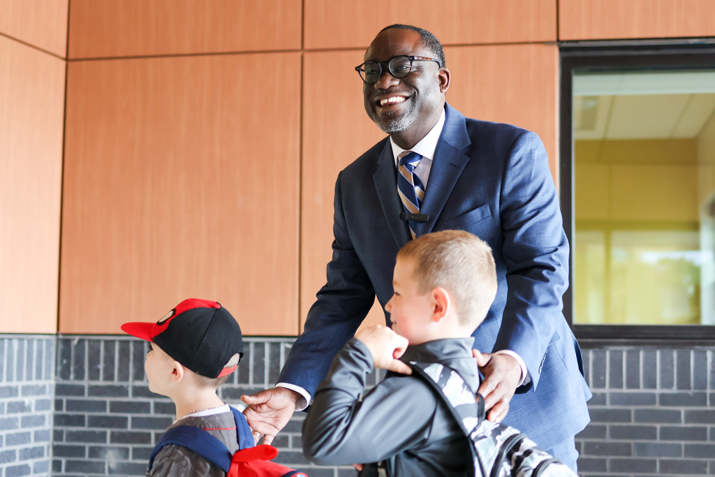 a man hugs two children outside a school