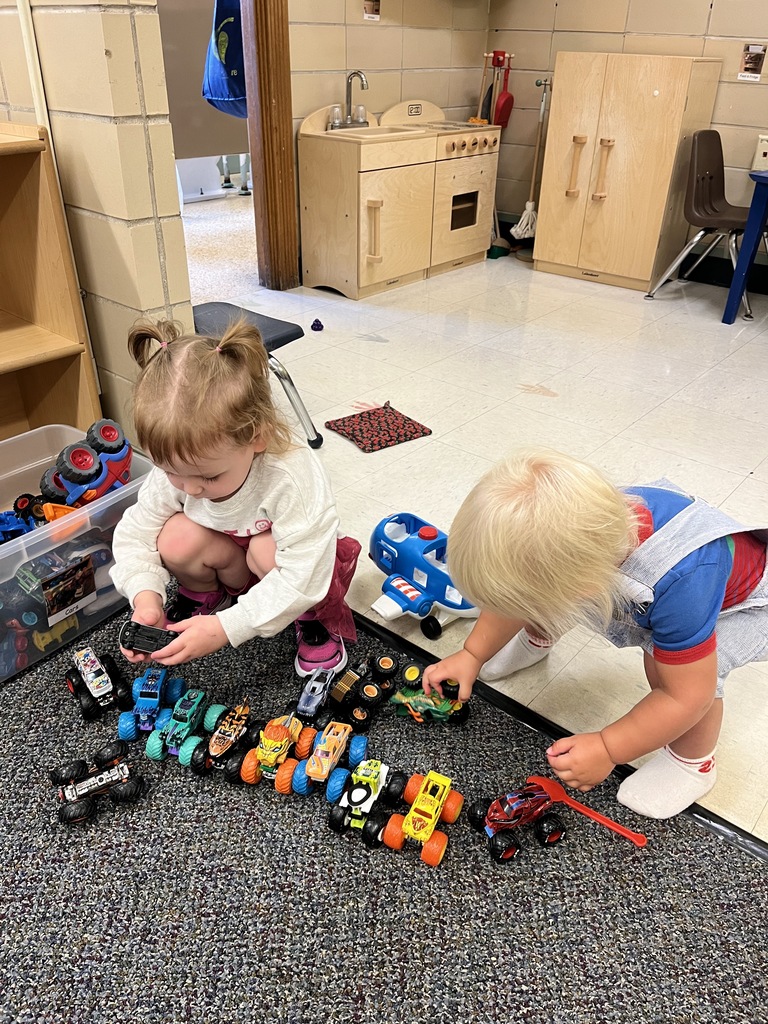 Toddlers lining up cars.