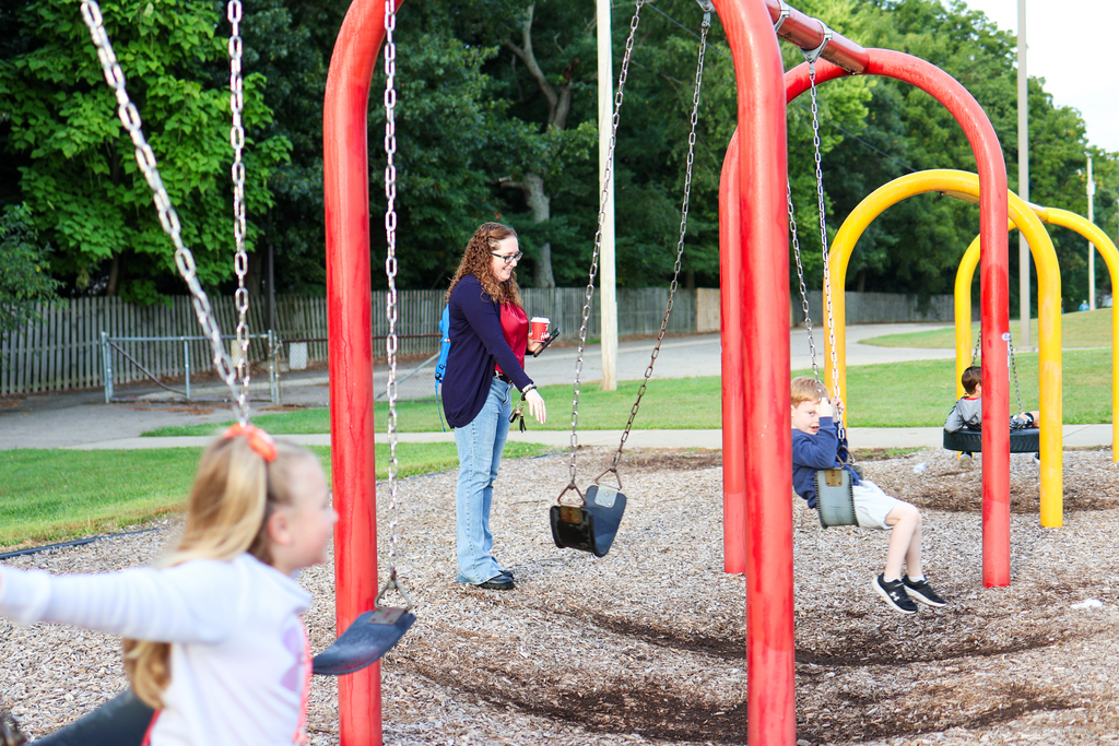 a mom pushes her child on a swingset