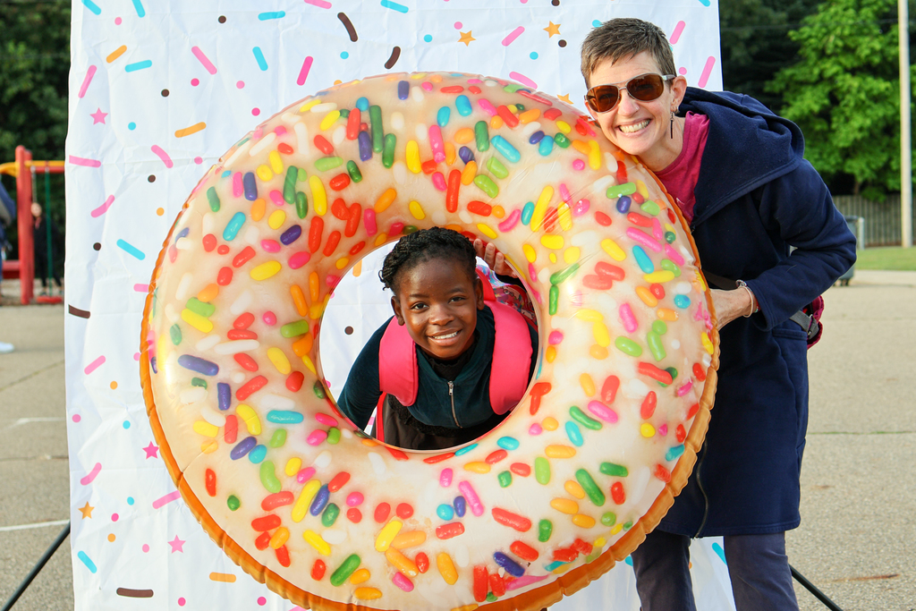a woman and her daughter pose for a photo with an inflatable donut