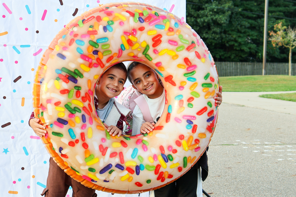 two kids pose for a photo with an inflatable donut