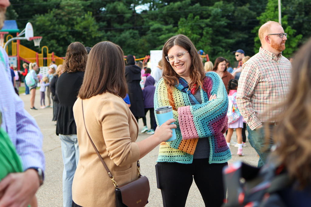 a woman smiles at another person standing outside