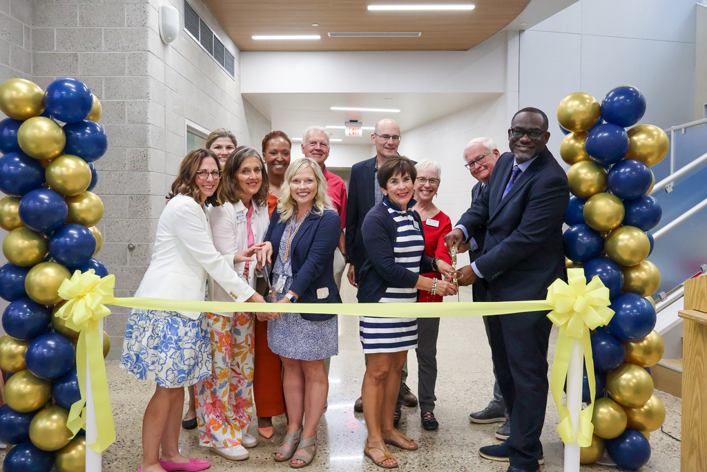 a group of people pose for a photo at a ribbon cutting ceremony