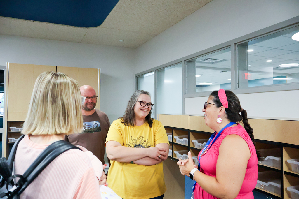 a woman smiles at another woman standing in a  classroom