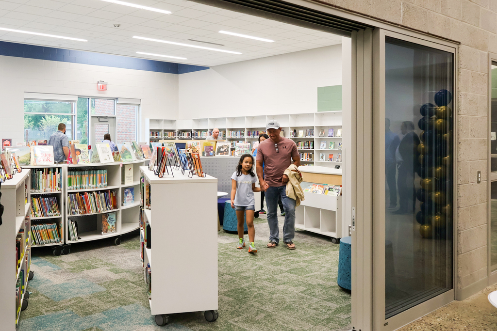 a man and daughter walk through a school library
