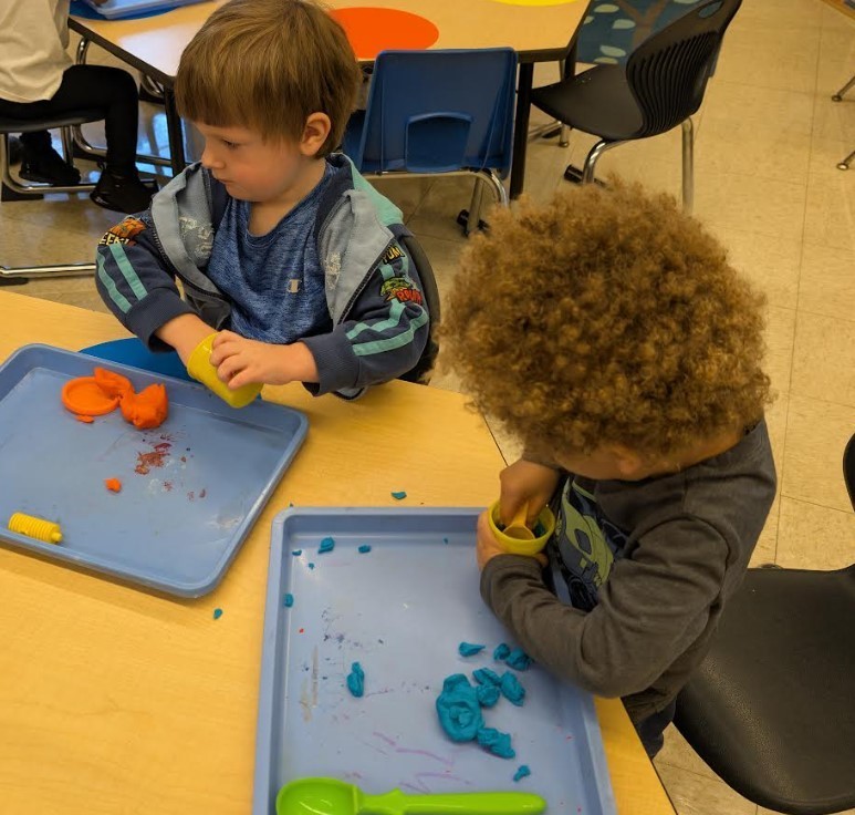 Two boys playing with playdough together.