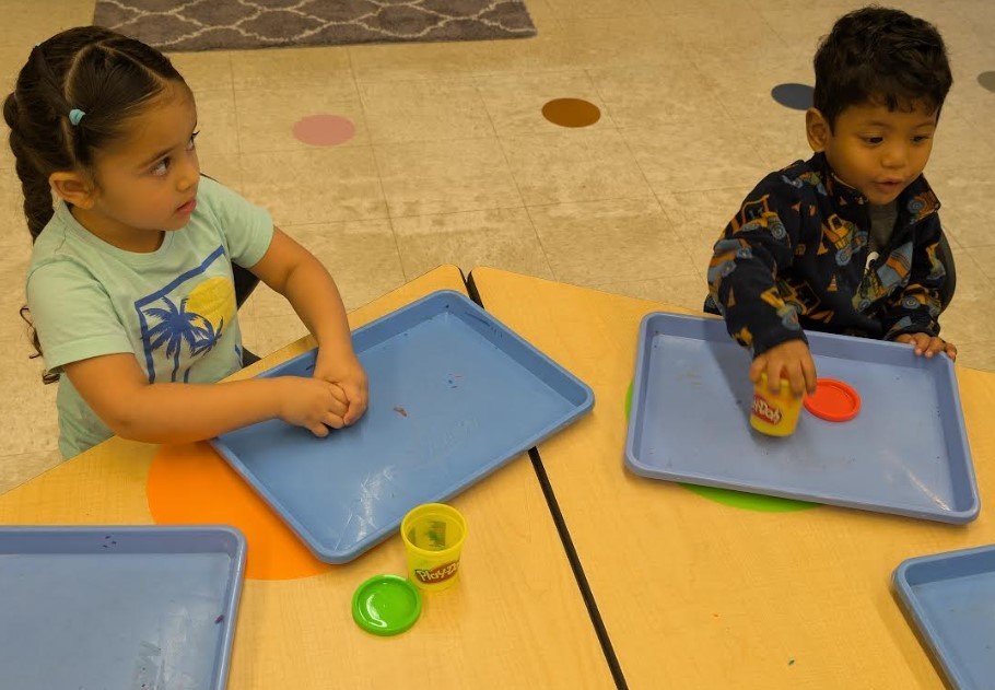 Two Three Year Olds playing with playdough.