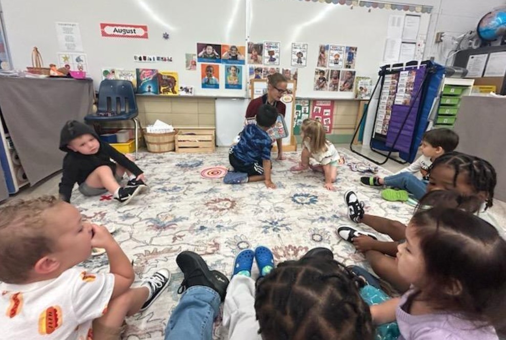 Three Year olds sitting on a rug together.