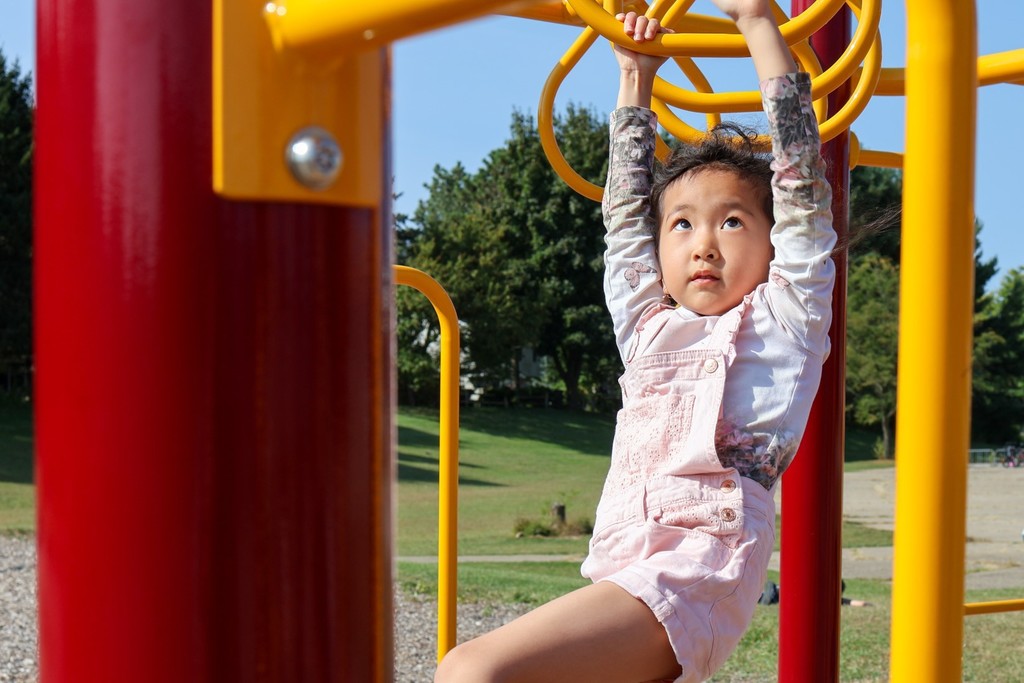 a girl crossing the monkey bars on a playground