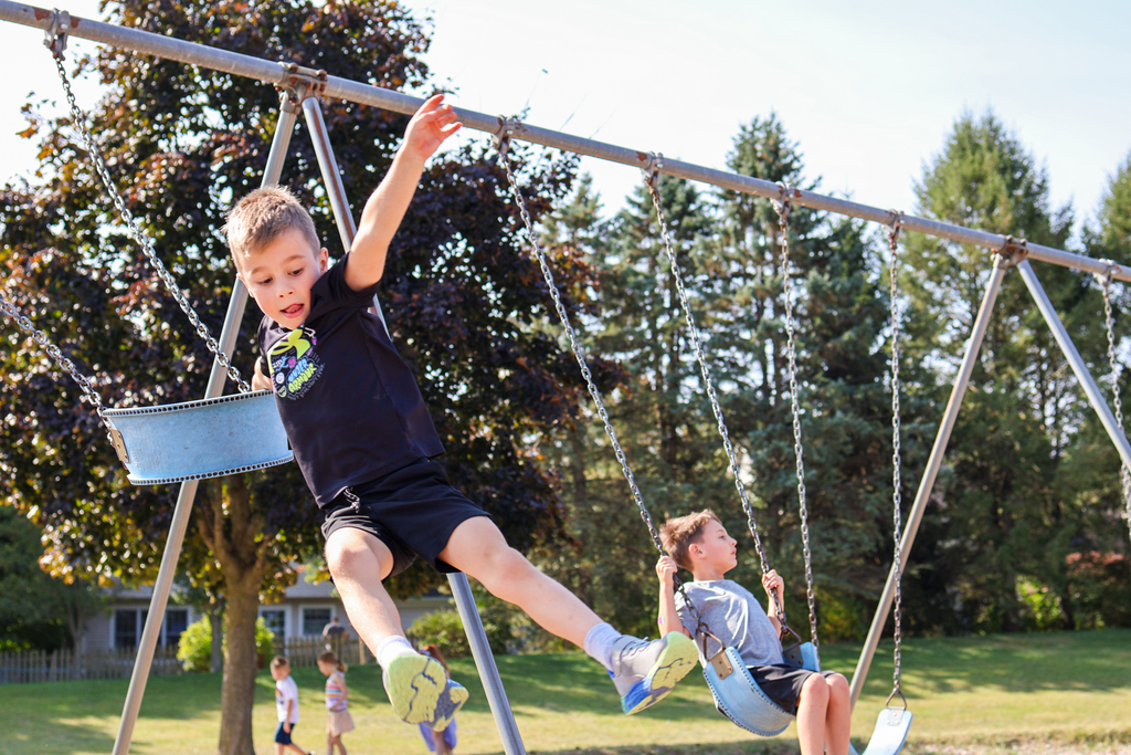 a boy jumping off the swings