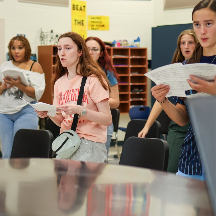 girls singing in a choir in front of a piano