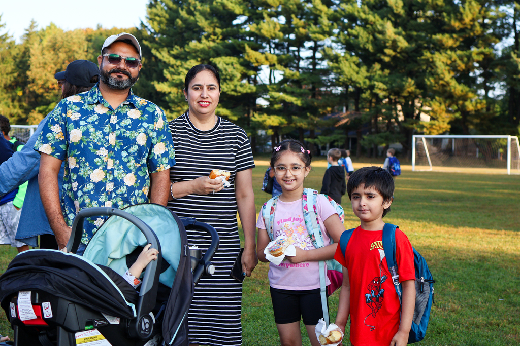 a family smiles for a photo outside an elementary school