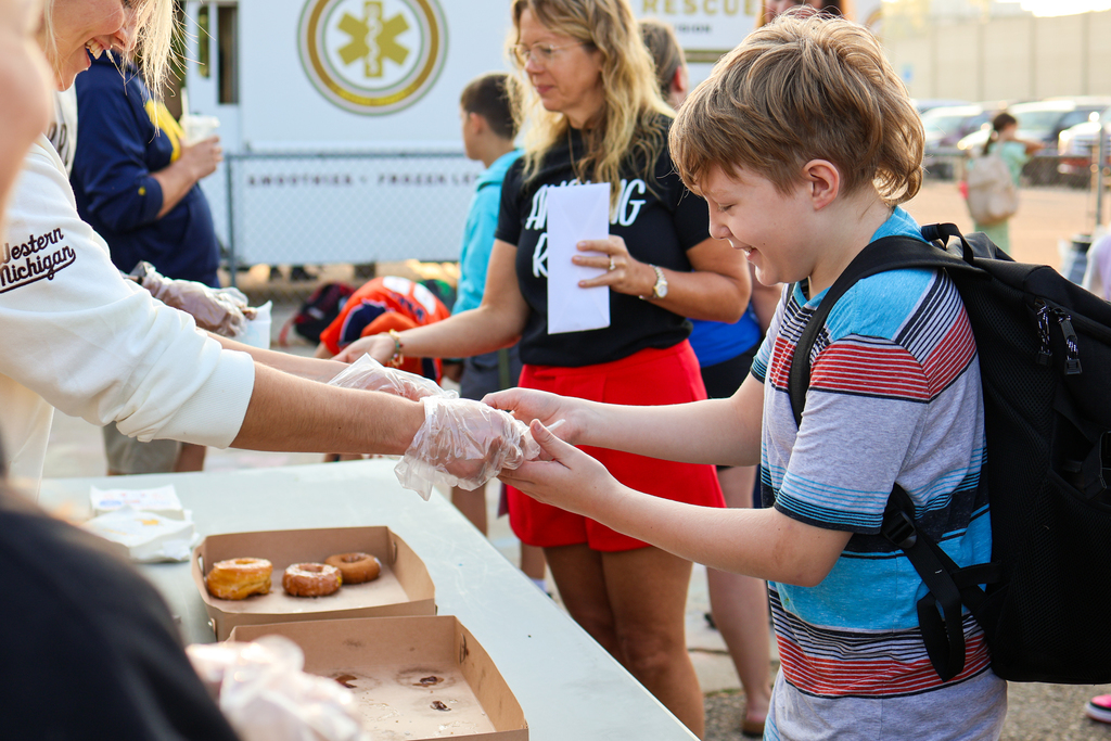 a boy smiles as he takes a donut from an adult