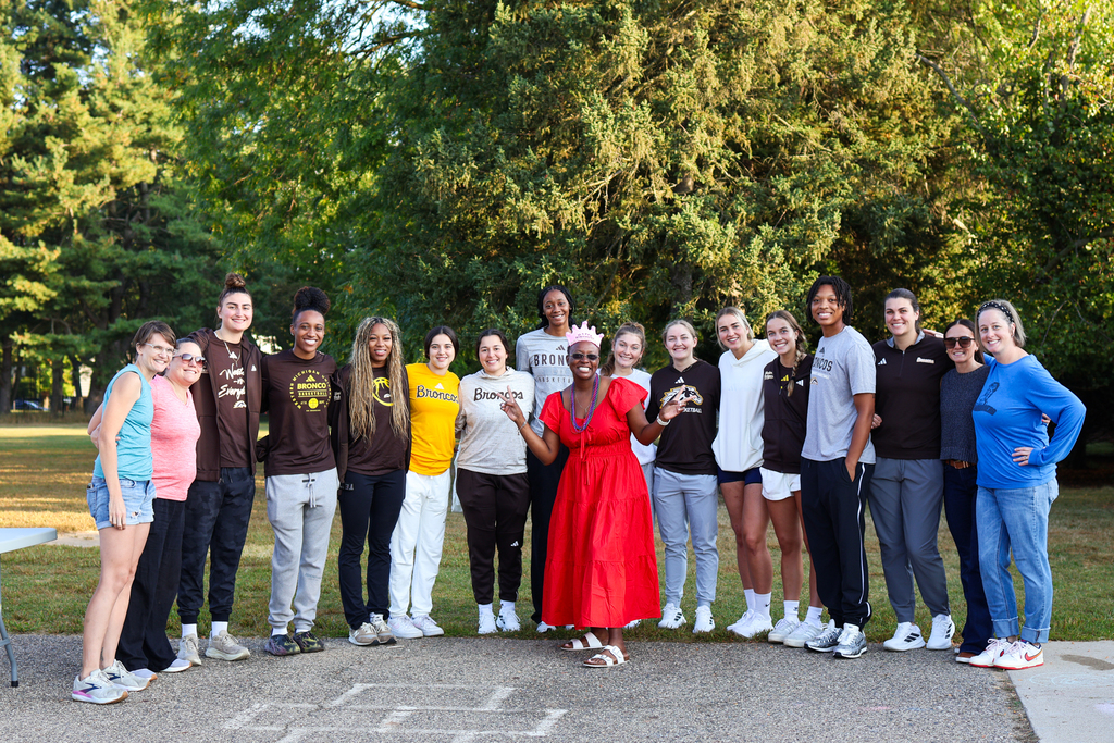 a large group of people pose for a photo in front of trees