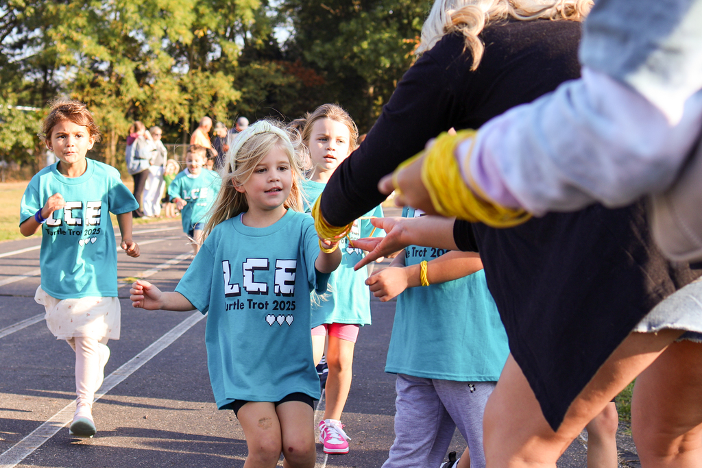 a girl accepts a bracelet from adults on the side of a track